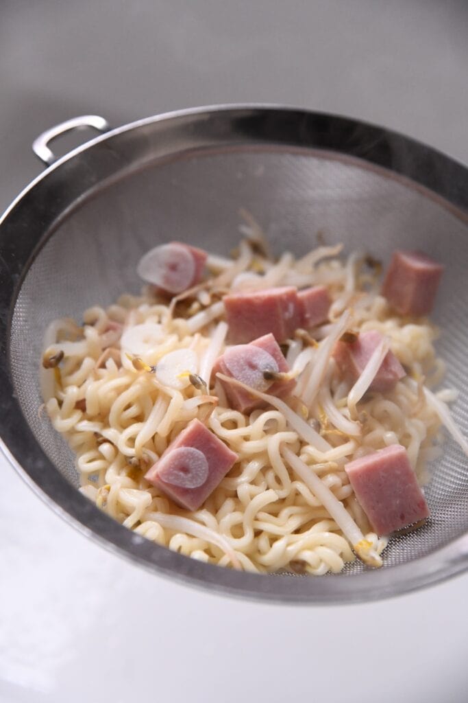 noodles, spam, and beansprouts in a strainer
