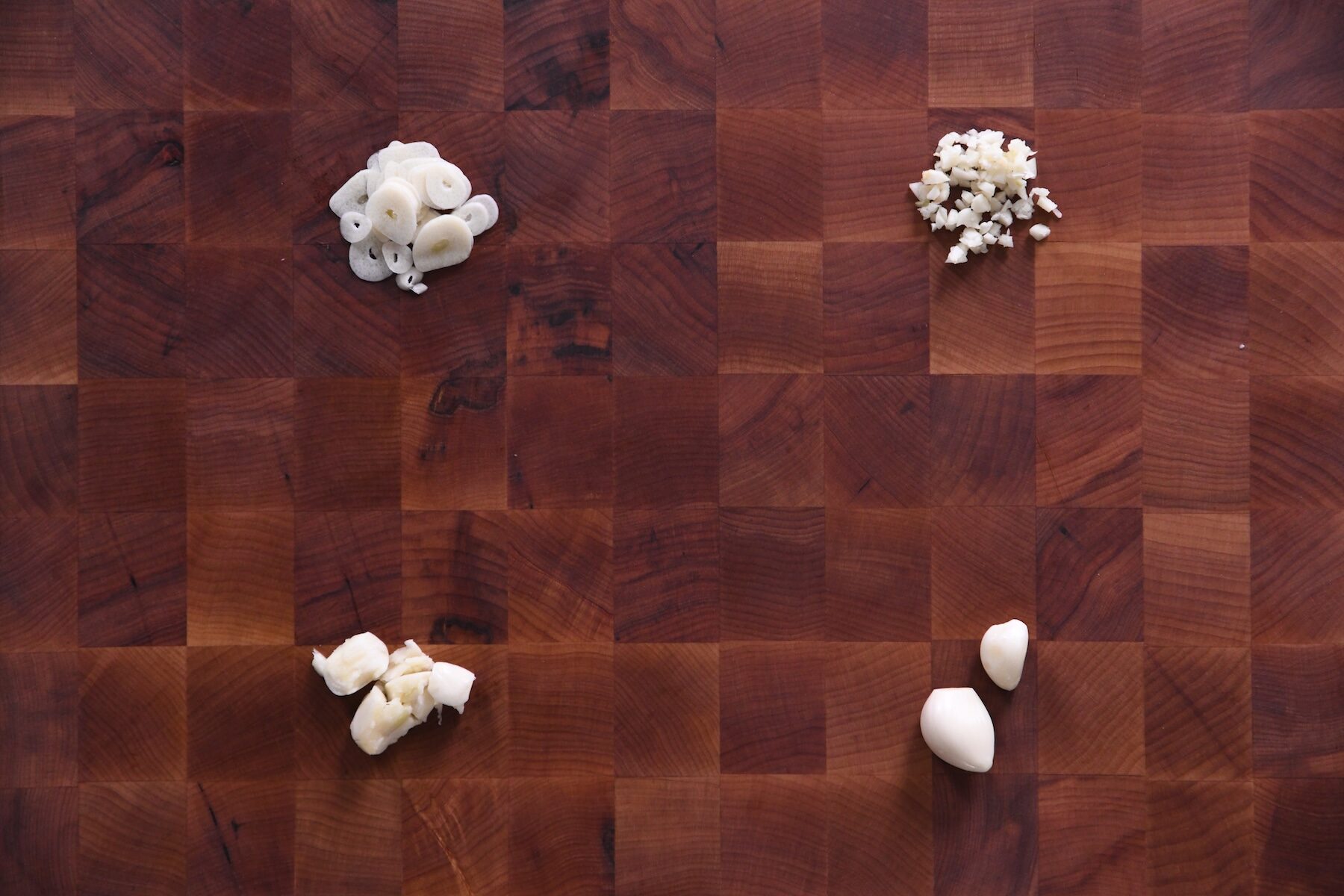 sliced garlic, minced garlic, smashed garlic, and whole garlic on cutting board