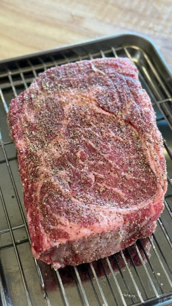 raw ribeye steak seasoned with salt and pepper