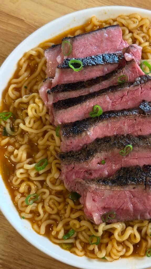 sliced steak on top of a bowl of ramen