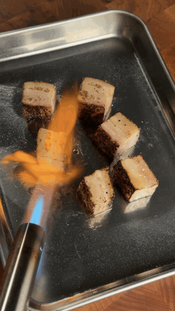 blow-torching cubed smoked pork belly