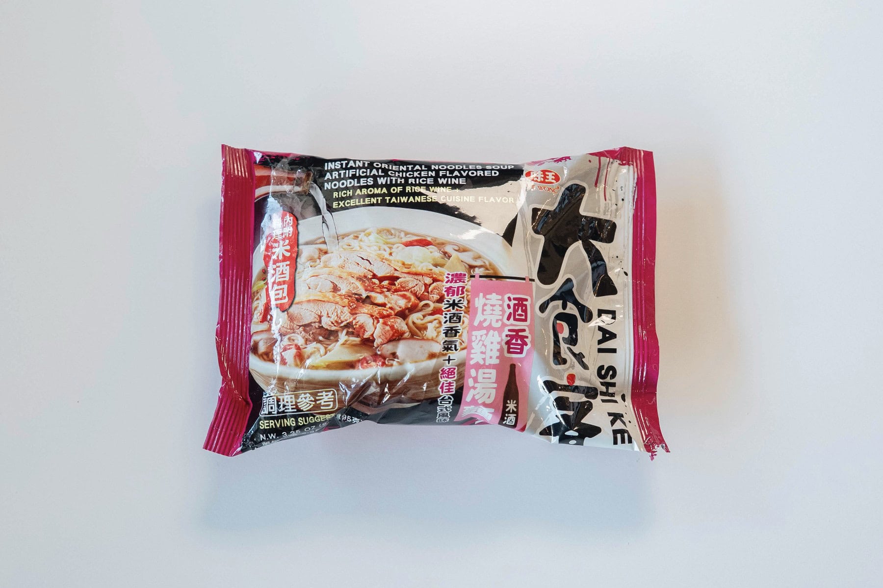 The magenta and black package of Ve Wong Dai Shi Ke Chicken Noodles with Rice Wine on a white surface, showing "Instant Oriental Noodles Soup Artificial Chicken Flavored Noodles with Rice Wine" and "Rich Aroma of Rice Wine + Excellent Taiwanese Cuisine Flavor" in white text, a serving suggestion of chicken noodles in a brown herbal broth, and large black Chinese characters 大食客 (Dai Shi Ke)