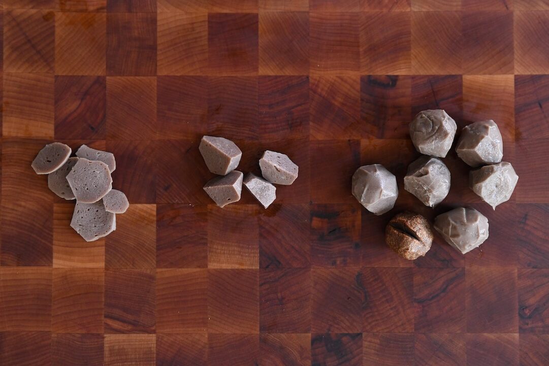 An overhead flat lay comparison of three different preparation styles for Vietnamese beef meatballs: thin slices (left), rough chunks/cubes (middle), and whole pieces (right), arranged on a dark wood cutting board.