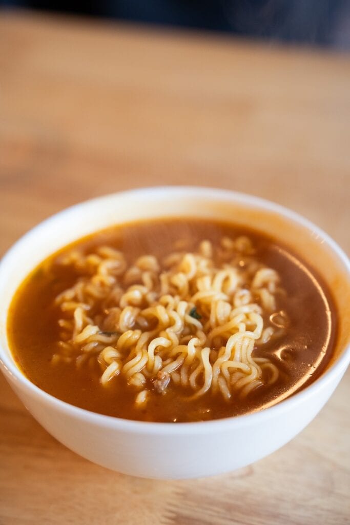 Nongshim Shin Ramyun Spicy Noodle Soup prepared in a white bowl with red broth