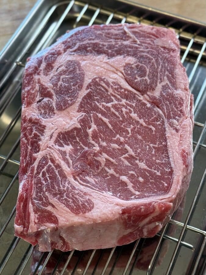 raw ribeye steak on wire rack