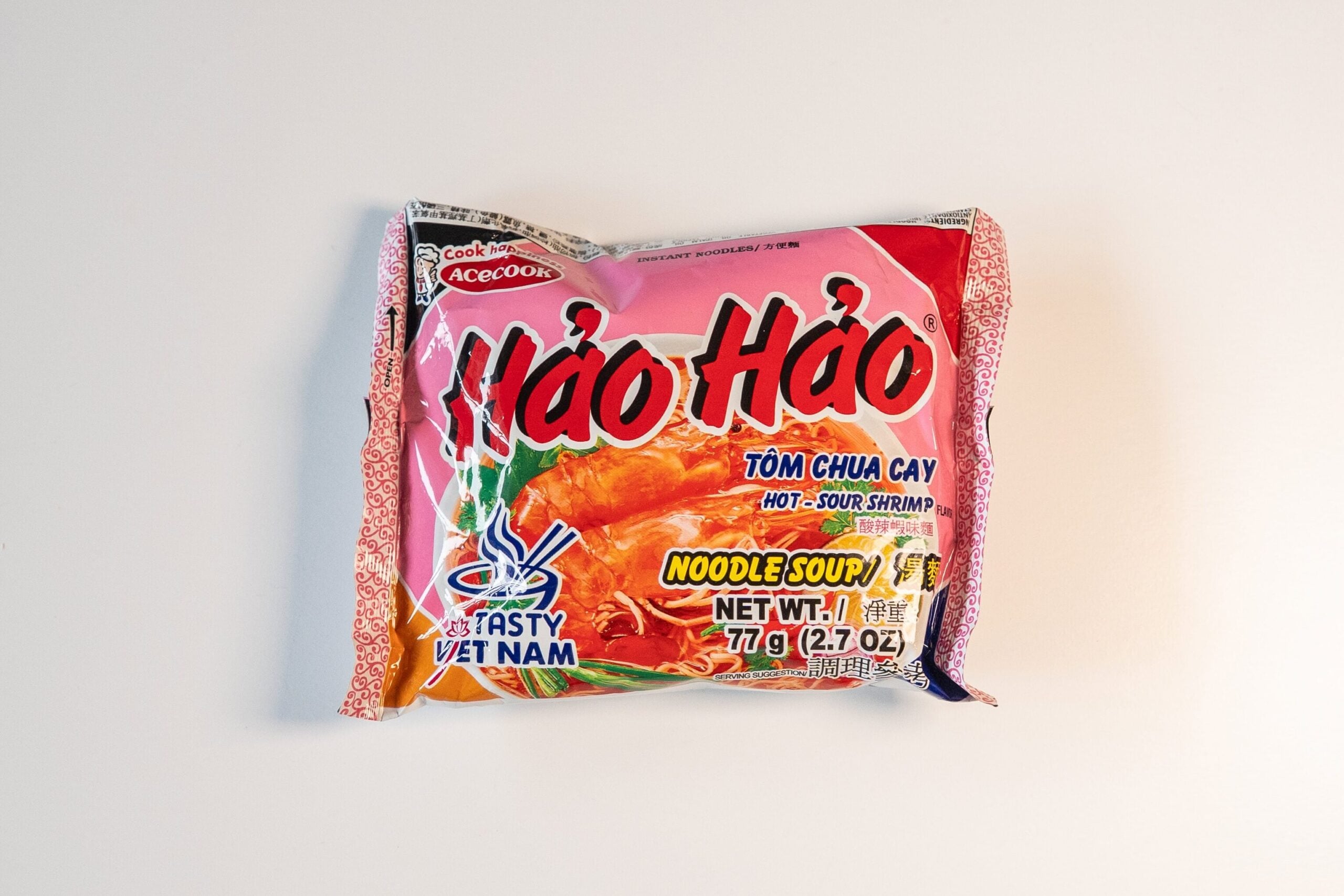 A pink package of Acecook Hao Hao Hot and Sour Shrimp instant noodles on a white surface.