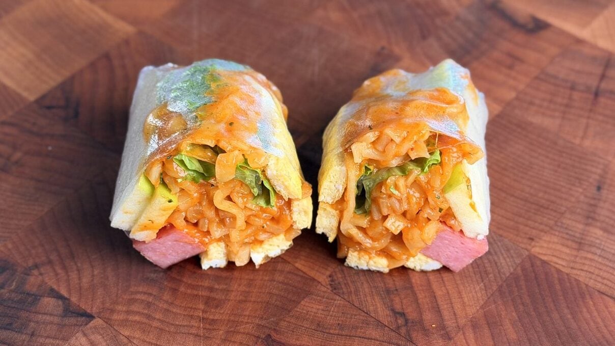 Green apple Buldak Carbonara spring rolls cut open on a wood cutting board with lettuce and apple visible through the rice paper