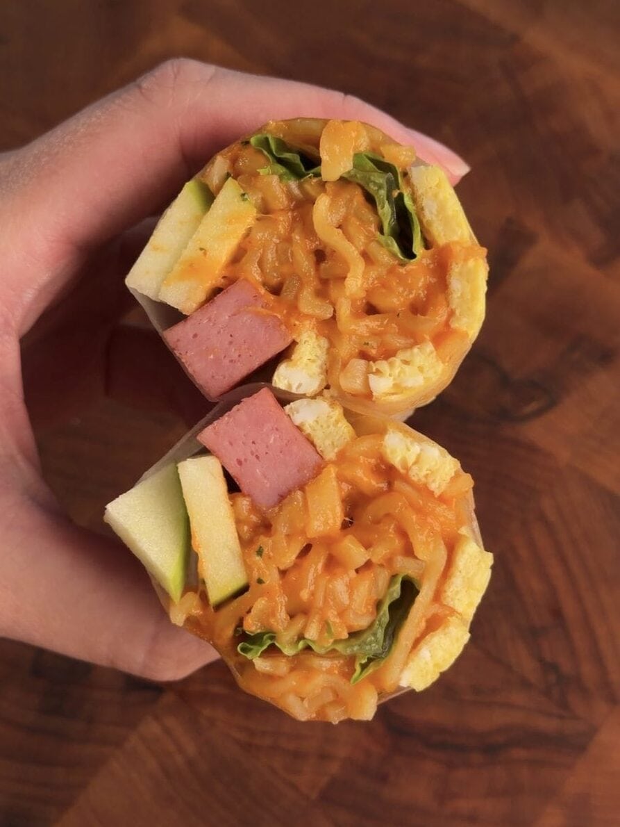 Green apple Buldak Carbonara spring rolls sliced on a bias showing creamy noodles, egg ribbons, Spam, and apple in cross section