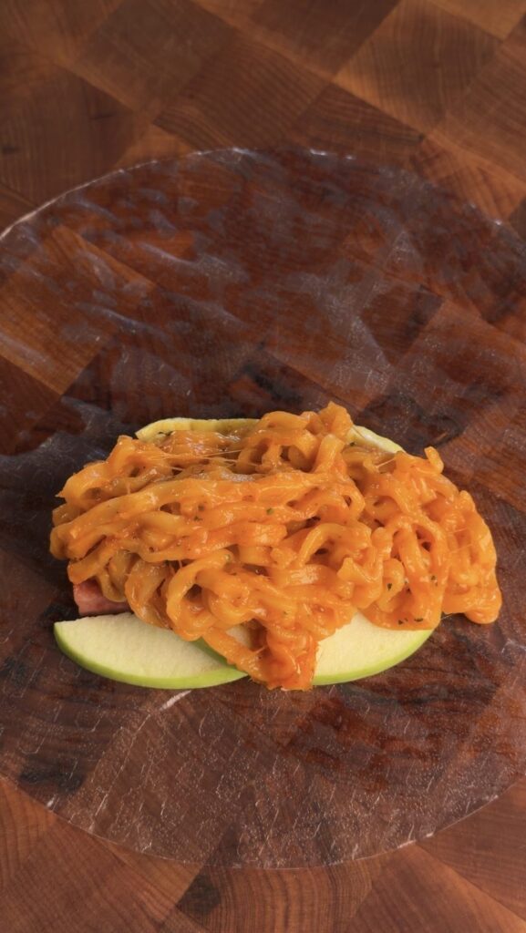 Creamy Buldak Carbonara noodles piled on a rice paper wrapper over green apple matchsticks