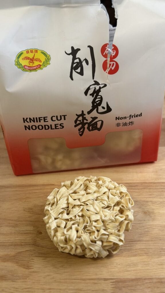 Package of non-fried knife-cut noodles with a dried noodle nest in front