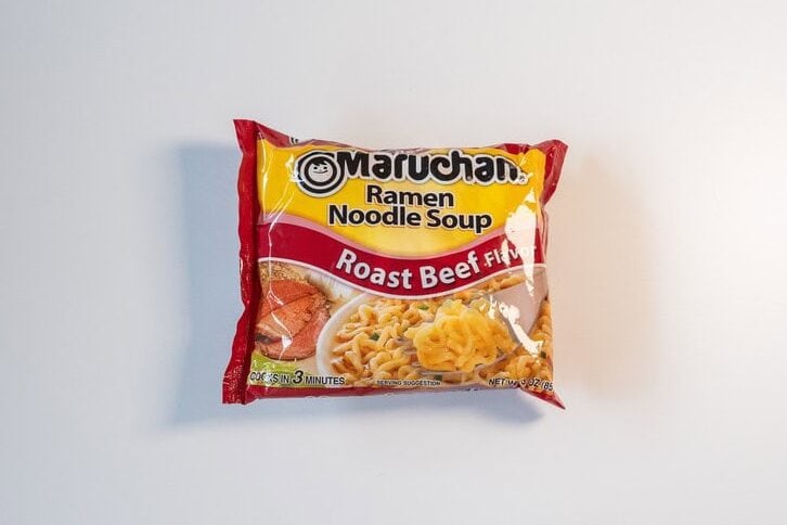Maruchan Roast Beef Ramen Noodle Soup package on gray background, red and yellow packaging with bowl of noodles in broth visible on front