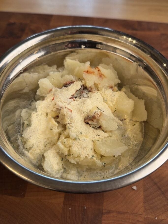 Scooped baked potato flesh in a metal bowl with the ramen seasoning added, ready to blend.