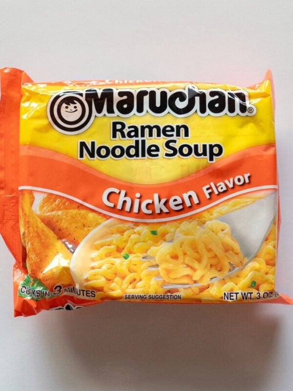 The orange and yellow package of Maruchan Chicken Flavor Ramen Noodle Soup on a white surface