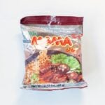 The front of the MAMA Stew Beef Flavor Instant Noodles package on a white surface, showing the maroon foil packaging with the red MAMA logo, gold Oriental Style Instant Noodles and Artificial Stew Beef Flavor text, and a photo of noodles with beef and mushroom in a dark broth. Net Wt. 2.12 oz (60g).