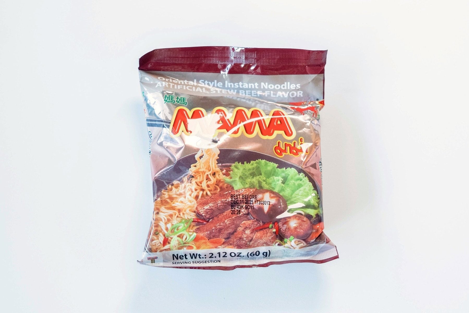 The front of the MAMA Stew Beef Flavor Instant Noodles package on a white surface, showing the maroon foil packaging with the red MAMA logo, gold Oriental Style Instant Noodles and Artificial Stew Beef Flavor text, and a photo of noodles with beef and mushroom in a dark broth. Net Wt. 2.12 oz (60g).