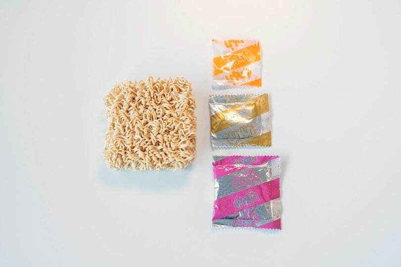 Noodle brick and three seasoning packets for MAMA Tom Yum Pork instant noodles