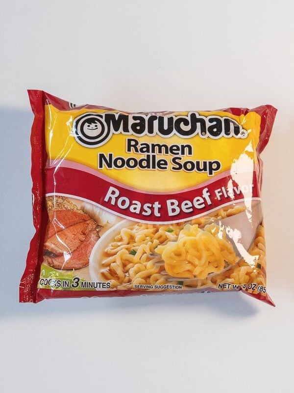 Maruchan Roast Beef Ramen Noodle Soup package on gray background, red and yellow packaging with bowl of noodles in broth visible on front