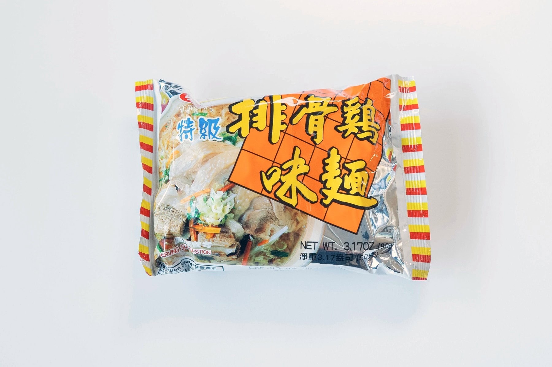 The Ve Wong Chicken & Pork Flavor Instant Noodle package on a white surface, showing a silver foil background with red and yellow striped edges, a bold orange grid with yellow Chinese characters reading 排骨雞味麵 (Pai Gu Ji Wei Mian / Pork Chop Chicken Flavor Noodle), and a serving suggestion of noodles with sliced pork and vegetables.