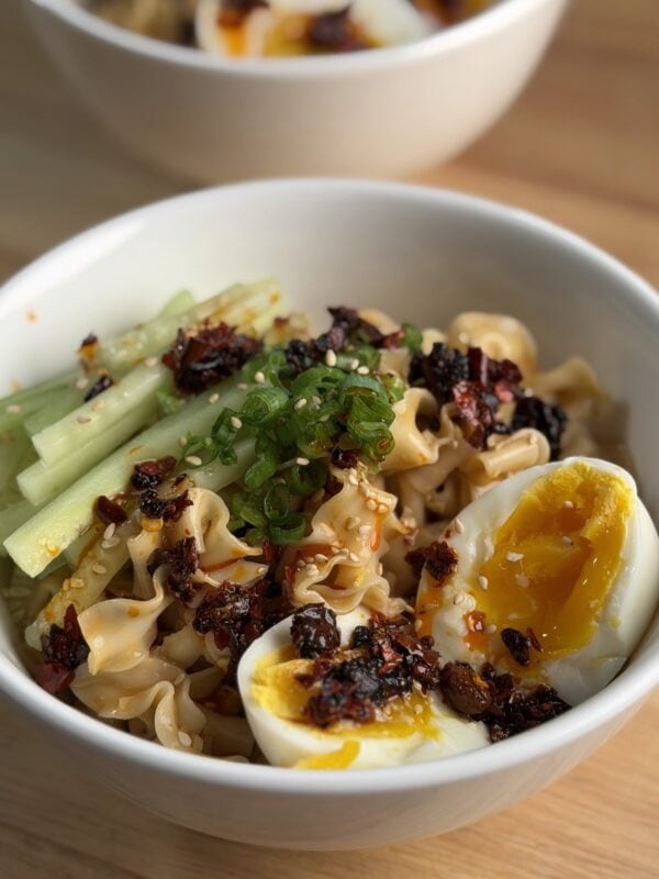 A bowl of Cold Sesame Chili Crisp Noodles with cucumber, chili crisp and a soft boiled egg